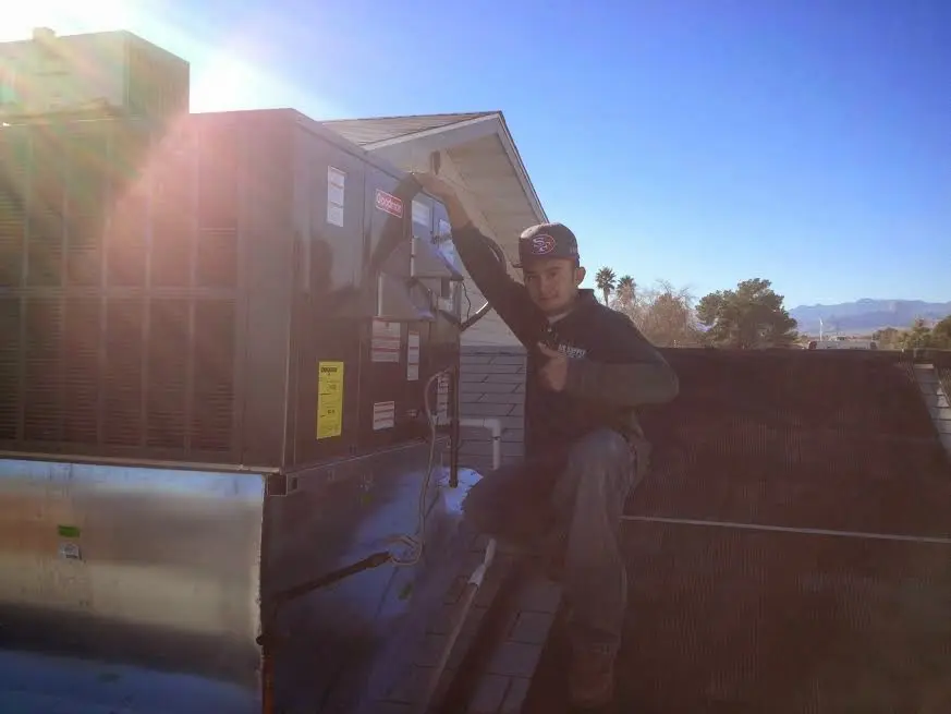 HVAC technician performing AC Tune-Up on a rooftop unit in Ontario